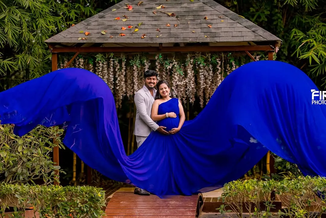 The power and beauty of motherhood are on full display in this shot. I use dramatic, flowing gowns like this vibrant blue one to create stunning, artistic maternity portraits. This was taken at a garden location with a beautiful wooden gazebo in the background.