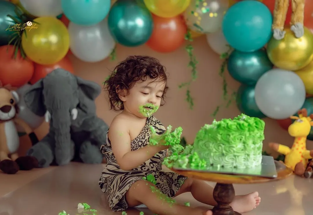 A classic cake smash moment. I love capturing the delightful mess and curiosity as a baby explores their first birthday cake in a fun, jungle-themed setup.