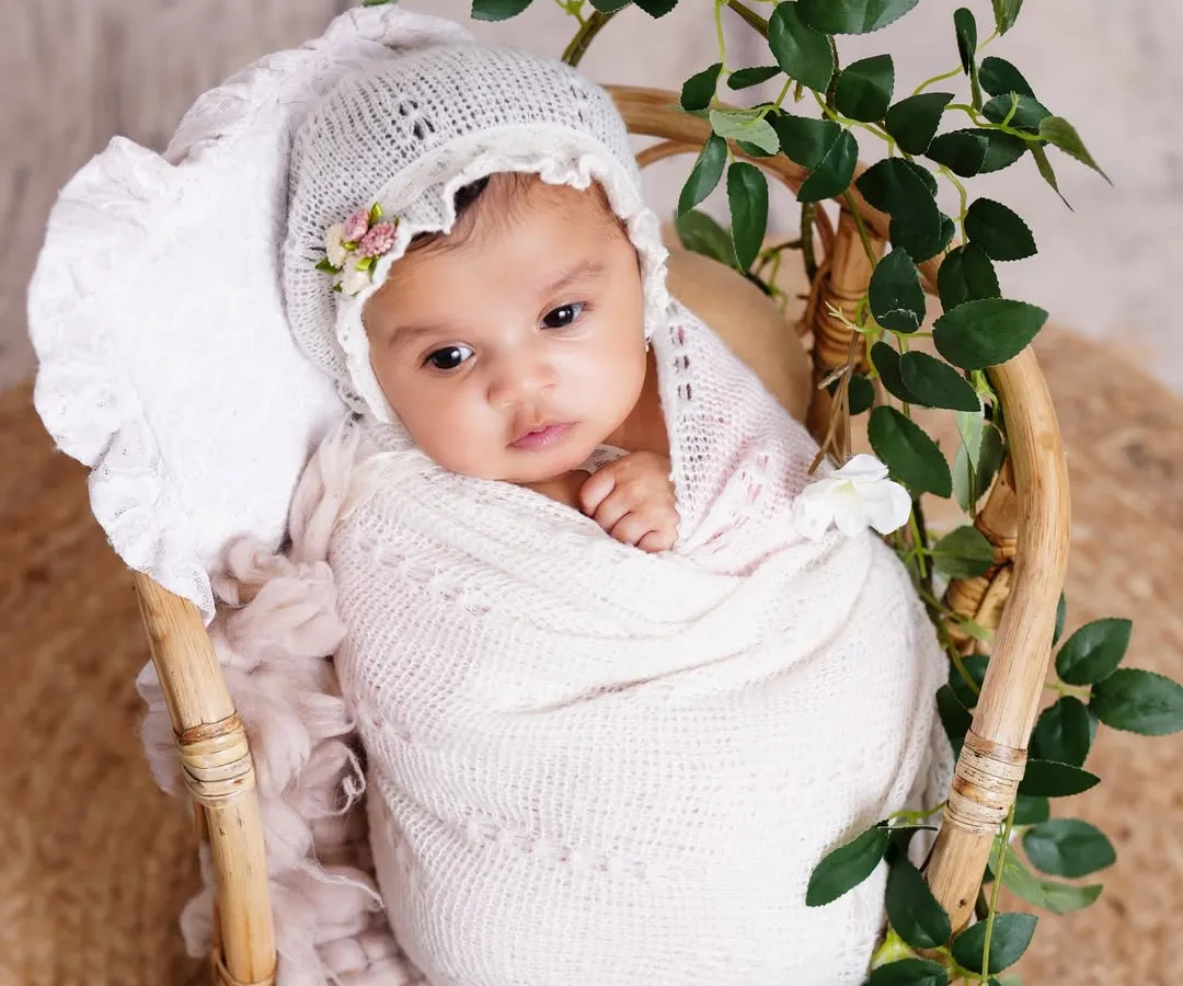 This is why I adore newborn photography. This peaceful baby is swaddled in soft white fabric, nestled in a rustic basket with delicate greenery, creating a pure and natural portrait.