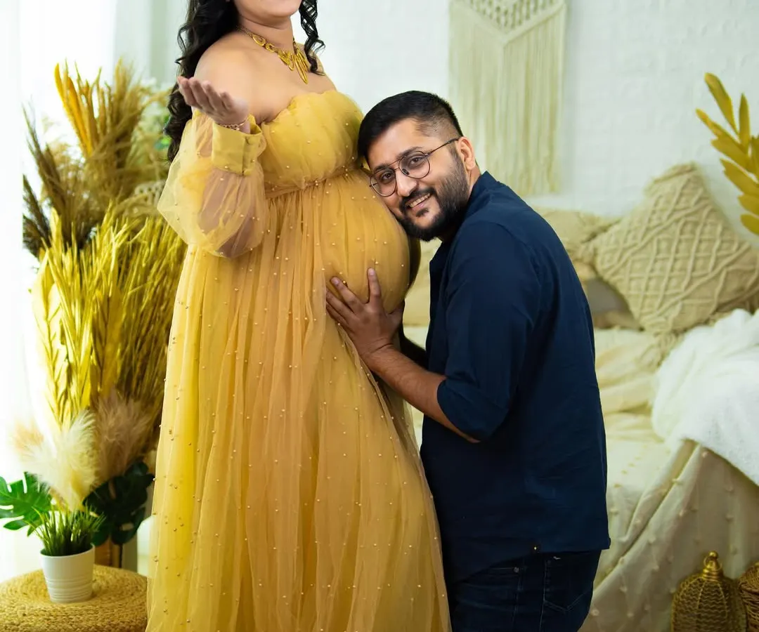 We love capturing the shared joy of expecting parents. This classic pose, with the partner listening to the baby bump, is a heartwarming way to document your connection and excitement. This shot was taken in our boho-chic studio setup.
