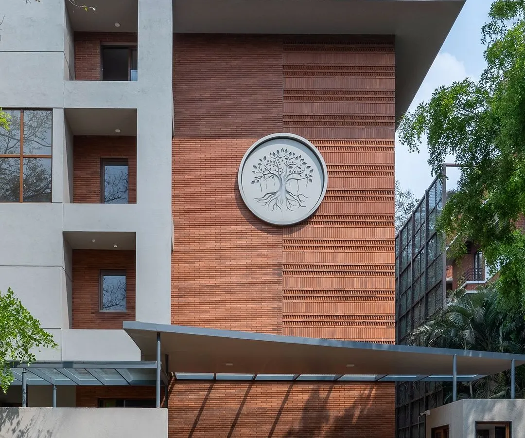 The facade of this Bengaluru apartment building showcases our approach to modern Indian architecture. The intricate exposed brickwork and custom tree-of-life emblem are a testament to our focus on craftsmanship and creating buildings with a unique identity.