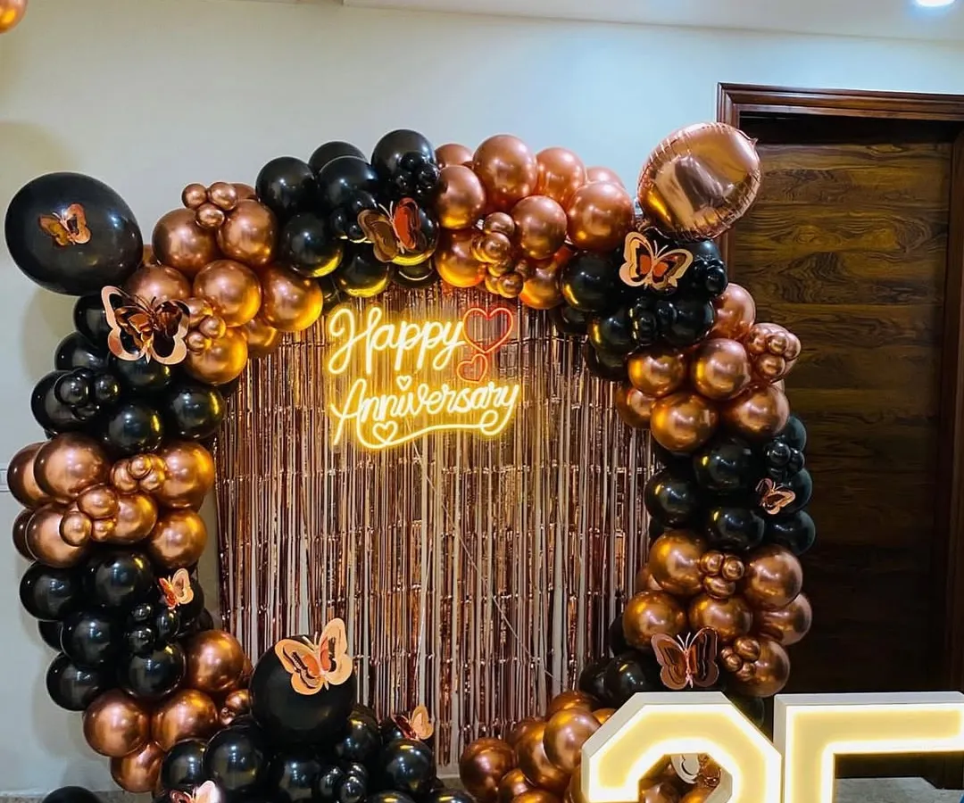 For milestone anniversaries, we design elegant backdrops that celebrate the occasion. This 25th-anniversary setup includes a circular balloon arch in black and rose gold, a custom neon sign, and large, illuminated marquee numbers.
