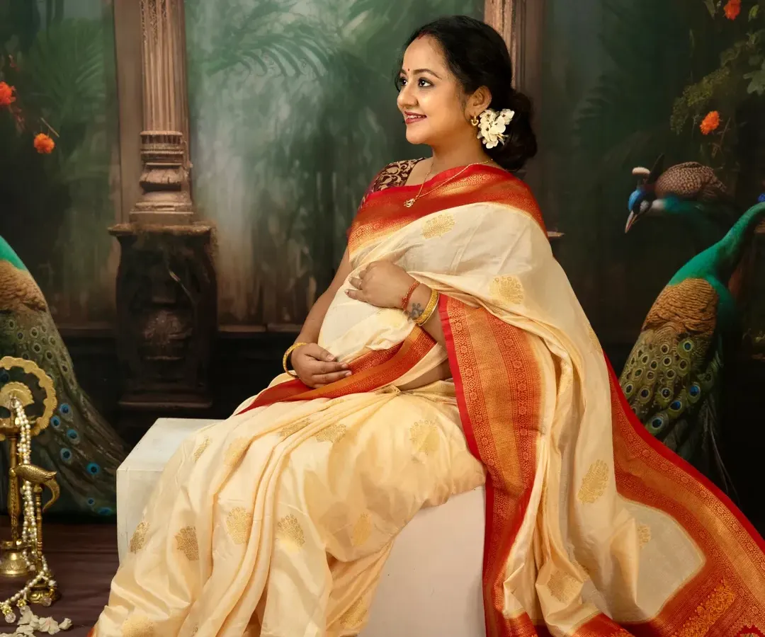 There is a divine grace in motherhood. For this traditional maternity portrait, we used a beautiful silk saree and classic props to create a timeless image. This solo shot focuses on the mother's serene profile and the elegant drape of the fabric over her baby bump.