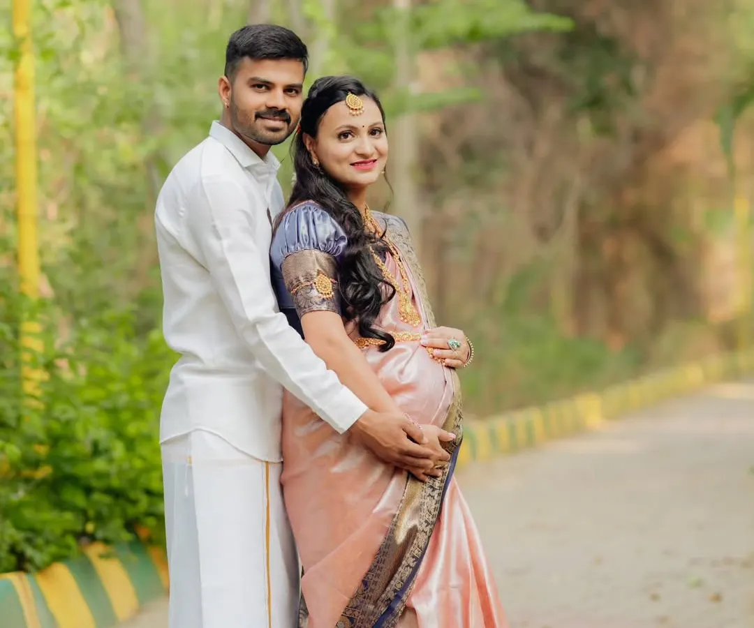 Embracing tradition with grace. This outdoor couple's portrait captures the elegance of a classic silk saree, blending cultural heritage with the natural beauty of a park setting for a timeless maternity photo.
