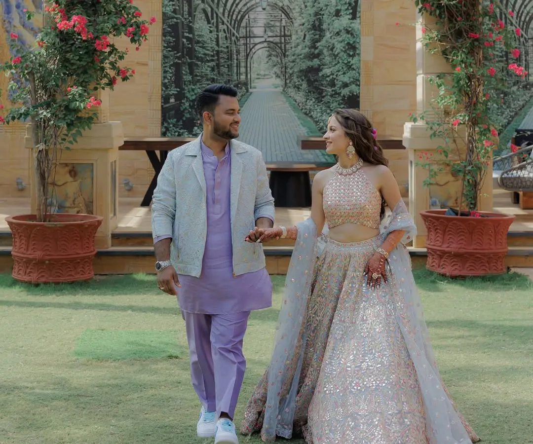 For their Haldi Carnival, we went with a playful and modern pastel theme. I designed a custom tone-on-tone lilac kurta set with a jacquard jacket for the groom, perfectly complementing the bride's bespoke pastel mirror-work lehenga. It was all about fresh colors and fun details, right down to their matching initialed sneakers.
