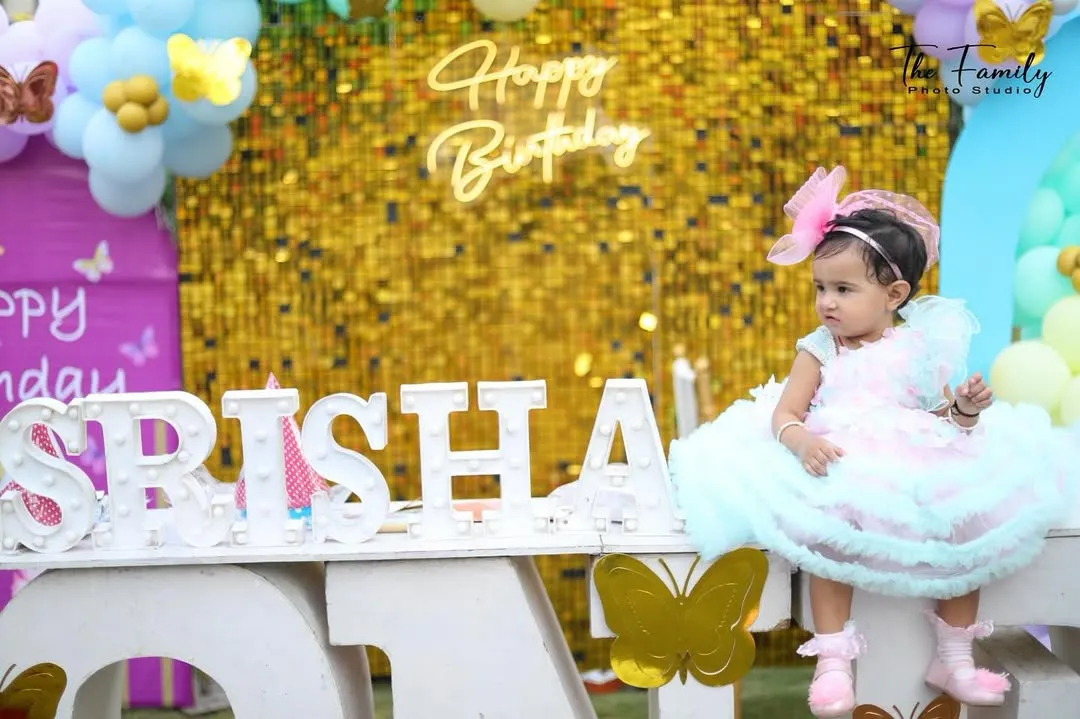 For this little girl's first birthday, I made sure to capture her with the beautiful decorations. This wide shot shows the full setup, from the custom light-up name sign to the golden sequin backdrop, making for a perfect memory of her special day.