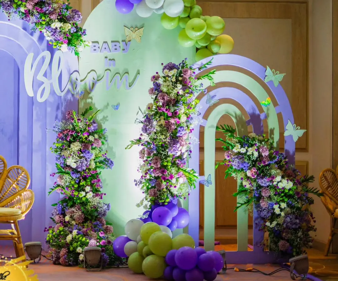 This 'Baby in Bloom' backdrop is one of my signature styles. I combine lush floral arrangements, soft pastel arches, and whimsical balloon garlands to create a picture-perfect setting for the mom-to-be. The rattan peacock chairs add a touch of bohemian opulence.
