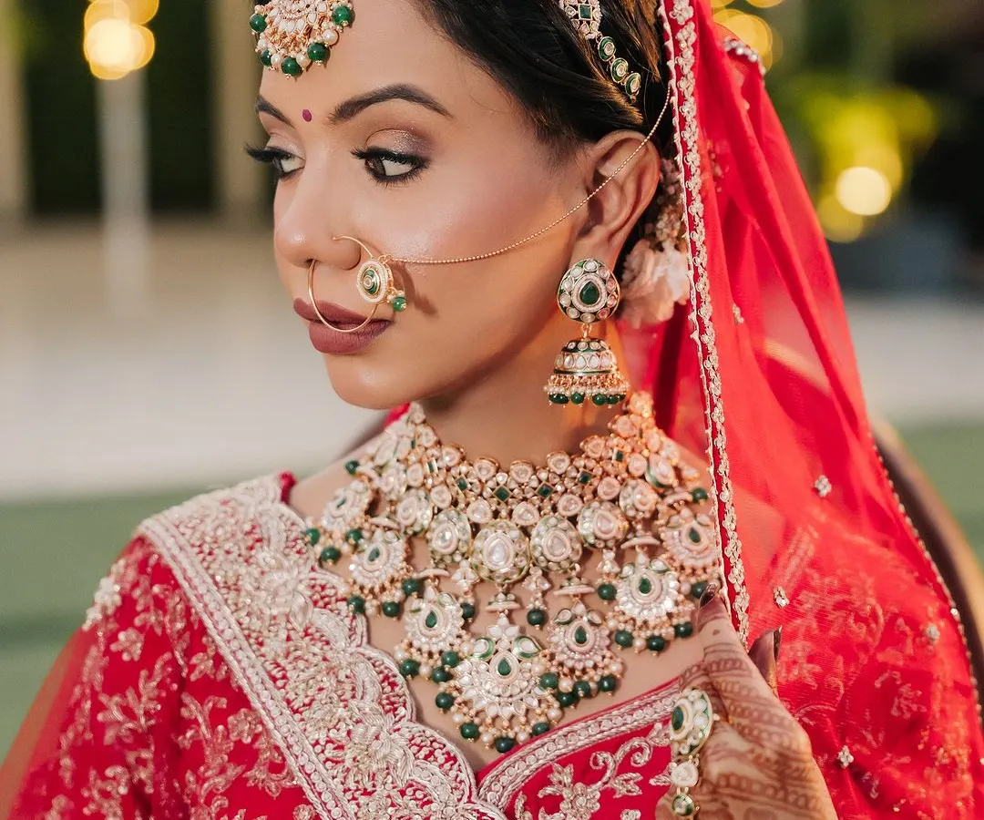 A close-up of this classic red bridal look. I focused on creating flawless, glowing skin and defining the eyes to complement her beautiful green and kundan jewellery. This is timeless elegance.