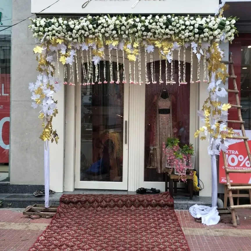 For the opening of a new boutique, we created this elegant entrance arch using a classic white and gold theme. The design features fresh white flowers, golden leaf accents, and hanging floral strings to welcome customers in style.