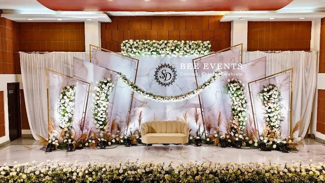 We specialize in creating modern and elegant reception stages that leave a lasting impression. This setup features a chic white and gold theme with a marble-finish backdrop, personalized monogram, and lush floral arrangements.