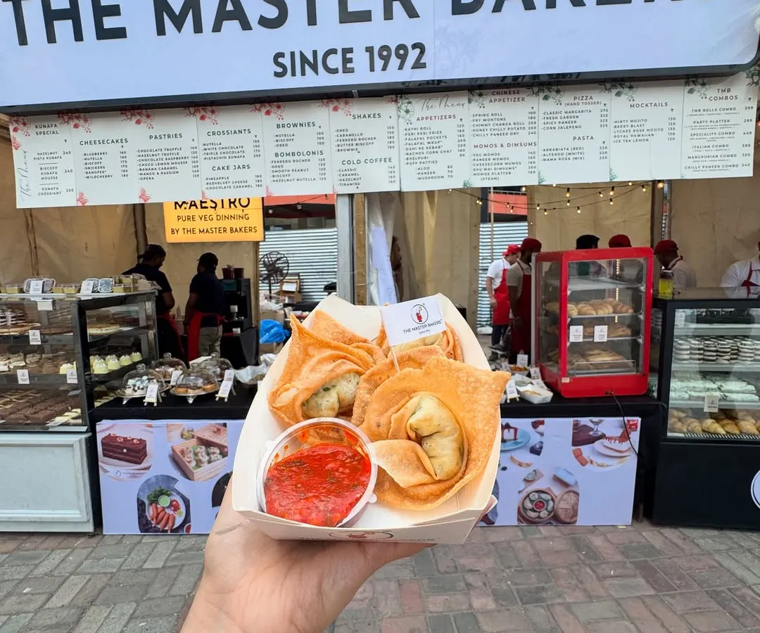A customer holding a fresh serving of our crispy fried wontons at our outdoor stall. These golden pockets are filled with a savory vegetable mix and served with a tangy dipping sauce, perfect for a quick and satisfying snack.