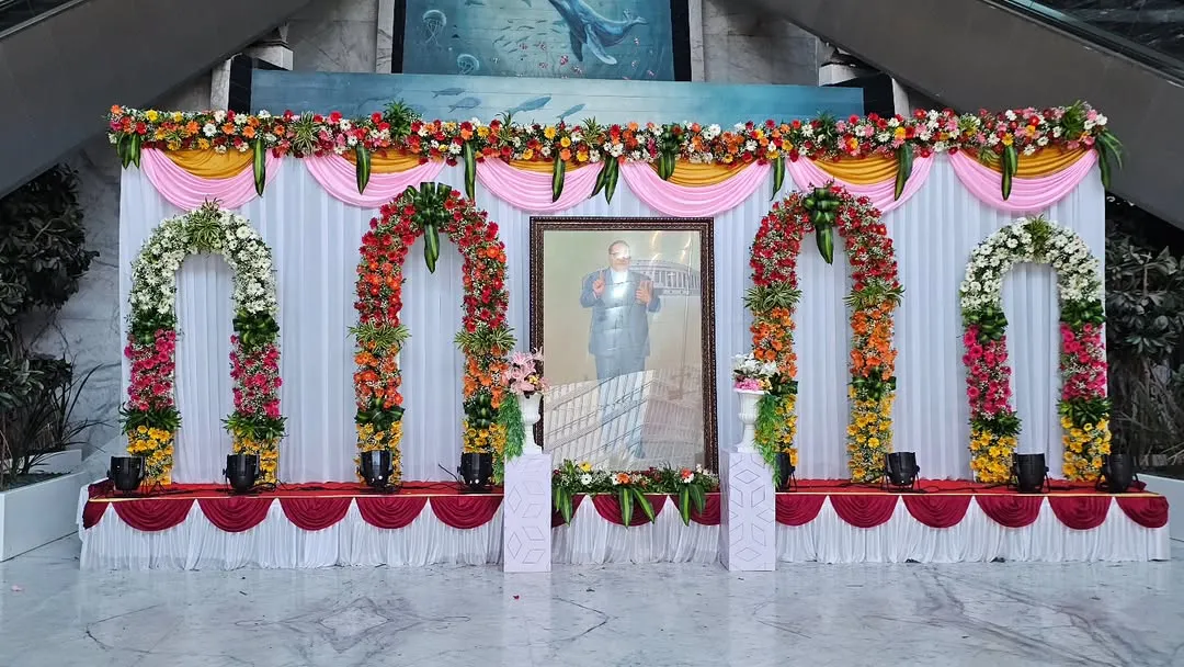 This is a complete stage setup I created for a formal tribute event at ONGC. The design includes a clean white backdrop with draped fabric, multiple floral arches, and professional stage lighting to create a respectful and distinguished ambiance.