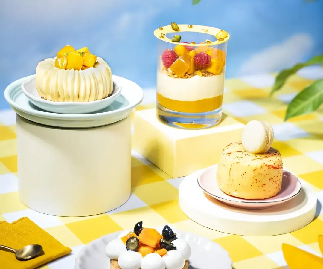 For this project, we built a whimsical summer picnic right in our studio to celebrate the king of fruits. Our art direction focused on creating a surreal, open-sky feeling with a fresh mango tree, a cheerful yellow checkered cloth, and a variety of mango desserts, from tarts to trifles, telling a complete story of a summer menu.