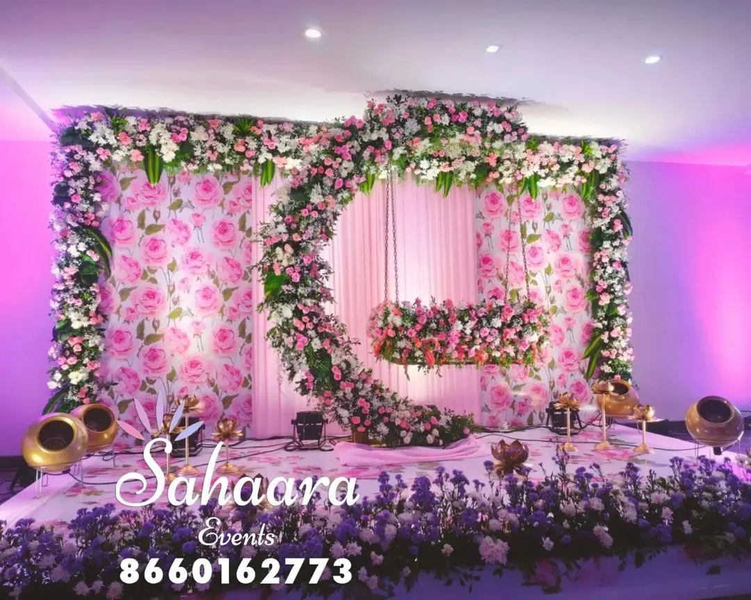 For a truly special naming ceremony or baby shower, we designed this breathtaking floral swing. The crescent moon shape, covered in soft pink and white flowers against a rose-patterned backdrop, creates a magical setting to welcome your little one.
