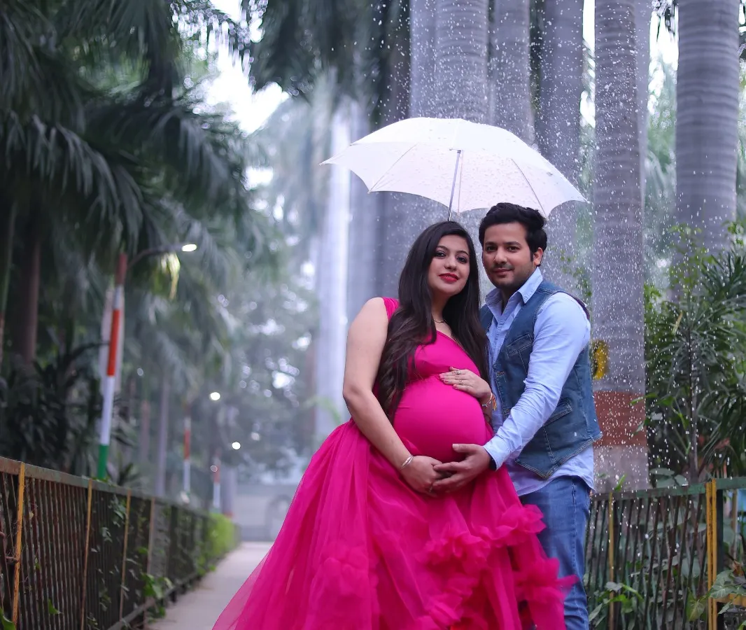 An outdoor maternity photoshoot in a beautiful park setting. I help couples celebrate their pregnancy with vibrant and dramatic portraits like this one, using flowing gowns to create a stunning visual.