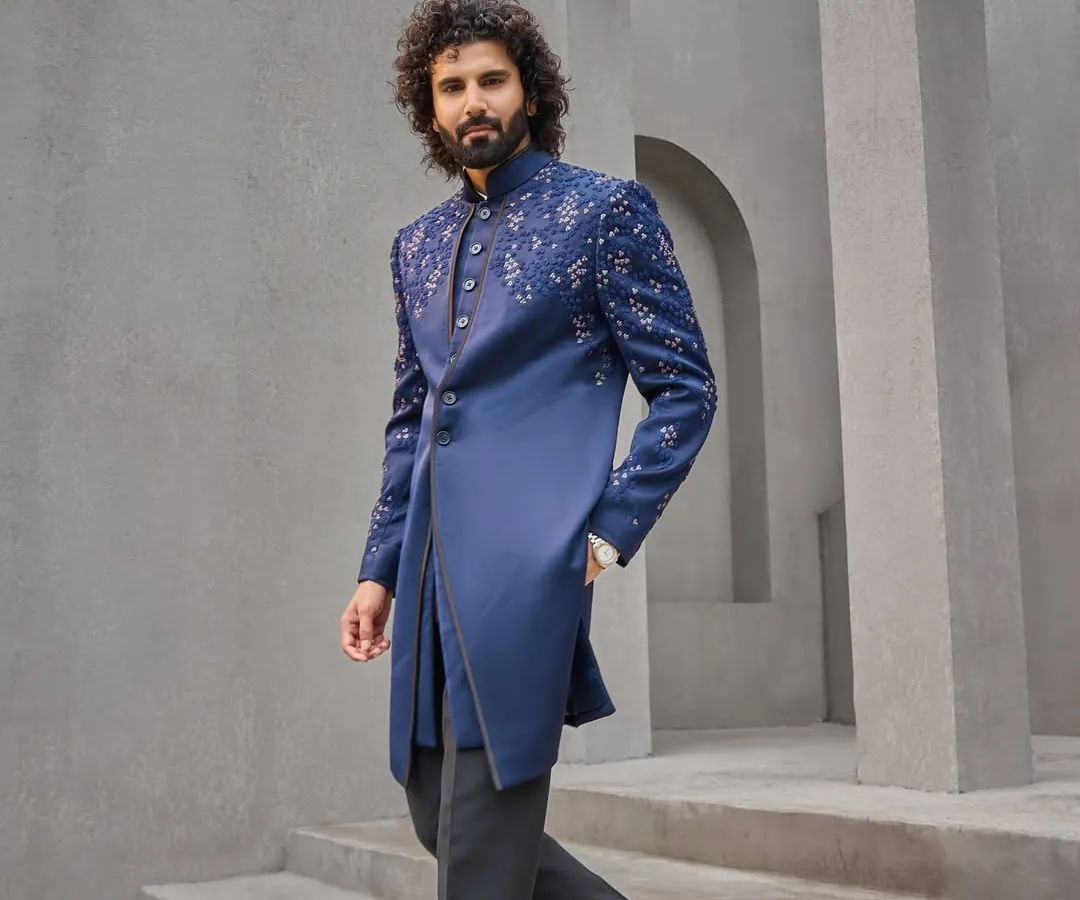 This is my modern take on the classic bandhgala. Crafted in a deep indigo, the asymmetrical cut and scattered embroidery on the shoulder and sleeve offer a contemporary edge, making it a perfect outfit for a Sangeet or reception.