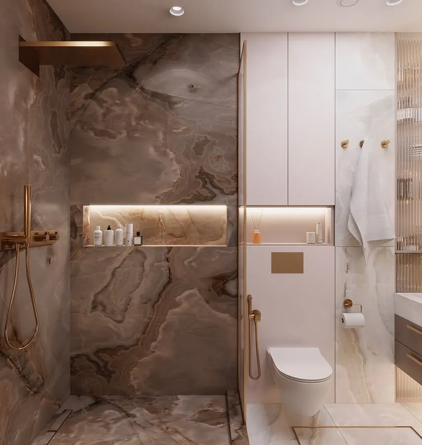 This bathroom design focuses on integrating luxury and practicality. We used dramatic, book-matched marble tiles for the wet area, complemented by warm LED lighting in the shower niche. The wall-mounted toilet and concealed cistern, paired with seamless overhead cabinets, maximize floor space and provide ample, hidden storage for a clutter-free look.