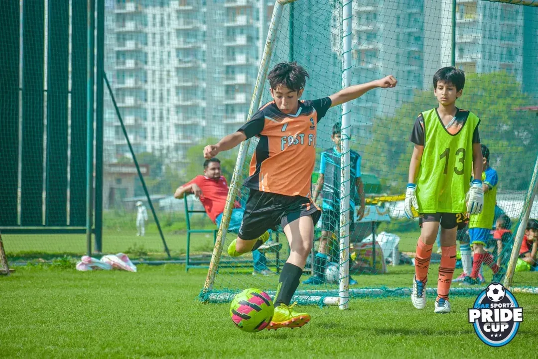 Here, a young footballer from our academy lines up a crucial shot on goal during the Pride Cup. We focus on creating opportunities for youth players to test their skills in real-match situations, building their confidence and love for the game.