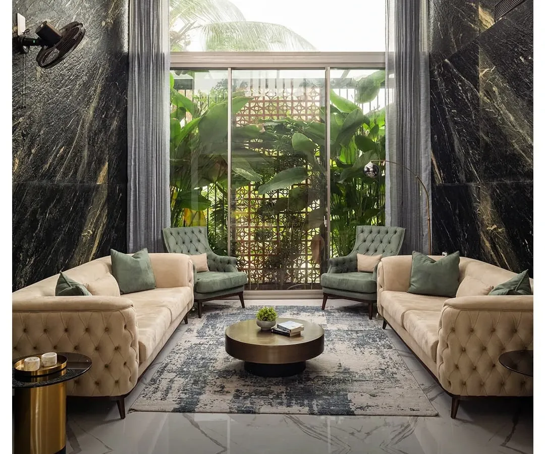 This double-height living room in the Rayyan project showcases how I blend luxury with comfort. The dramatic black marble walls and floor-to-ceiling windows create a space that is both grand and intimately connected to the lush greenery outside.
