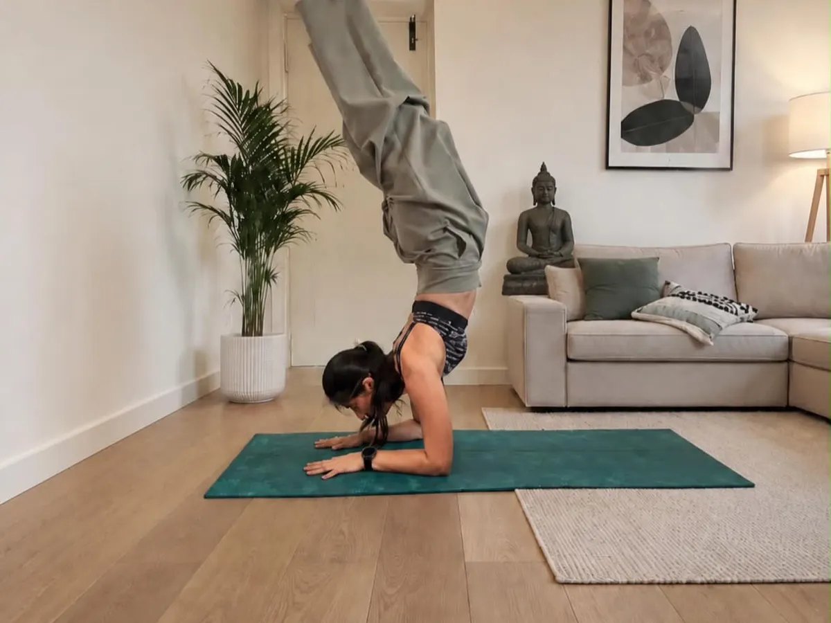 Forearm stand in a calm living room, legs folded overhead, shared on International Yoga Day 2026.