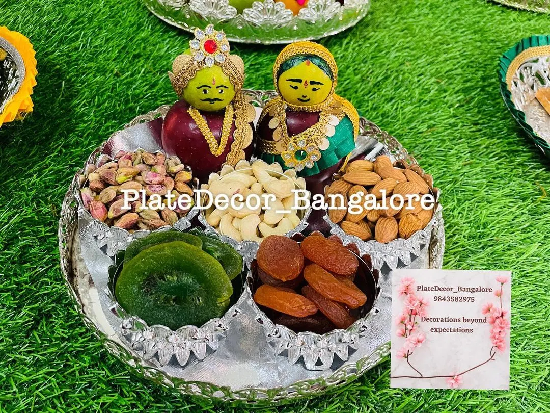 A close-up of one of my wedding platters, featuring traditional Marapachi Bommai figurines made from apples. The platter is filled with high-quality dry fruits like pistachios, cashews, and almonds, all arranged in an ornate silver tray.