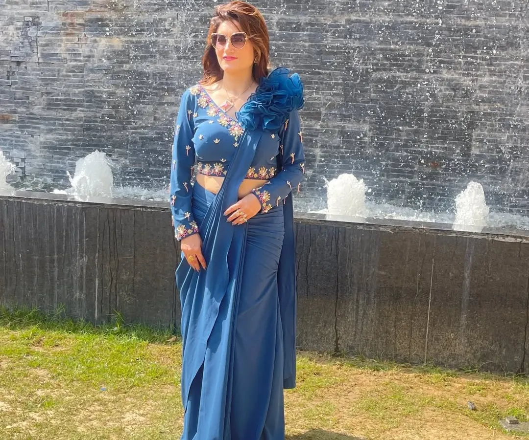 I love creating outfits that are both beautiful and practical. This pre-draped saree in a gorgeous shade of blue is exactly that. The blouse features intricate hand embroidery and a unique floral detail on the shoulder, giving you a sophisticated look without the hassle of draping.