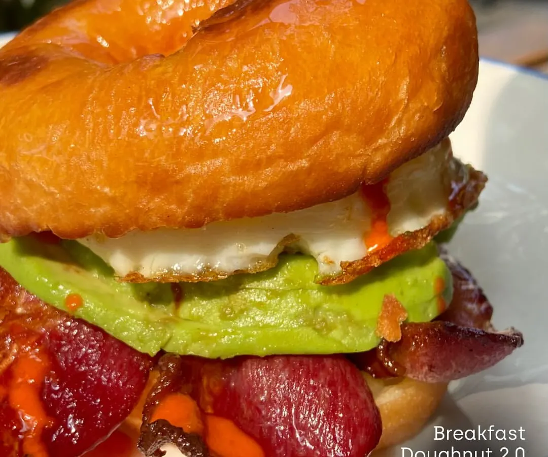 This is the Breakfast Doughnut 2.0 from our Padaria Prazeres pop-up. It's a perfect example of the playful yet delicious food I love to showcase: a maple-glazed doughnut with a fried egg, crispy bacon, avocado, and hot sauce.
