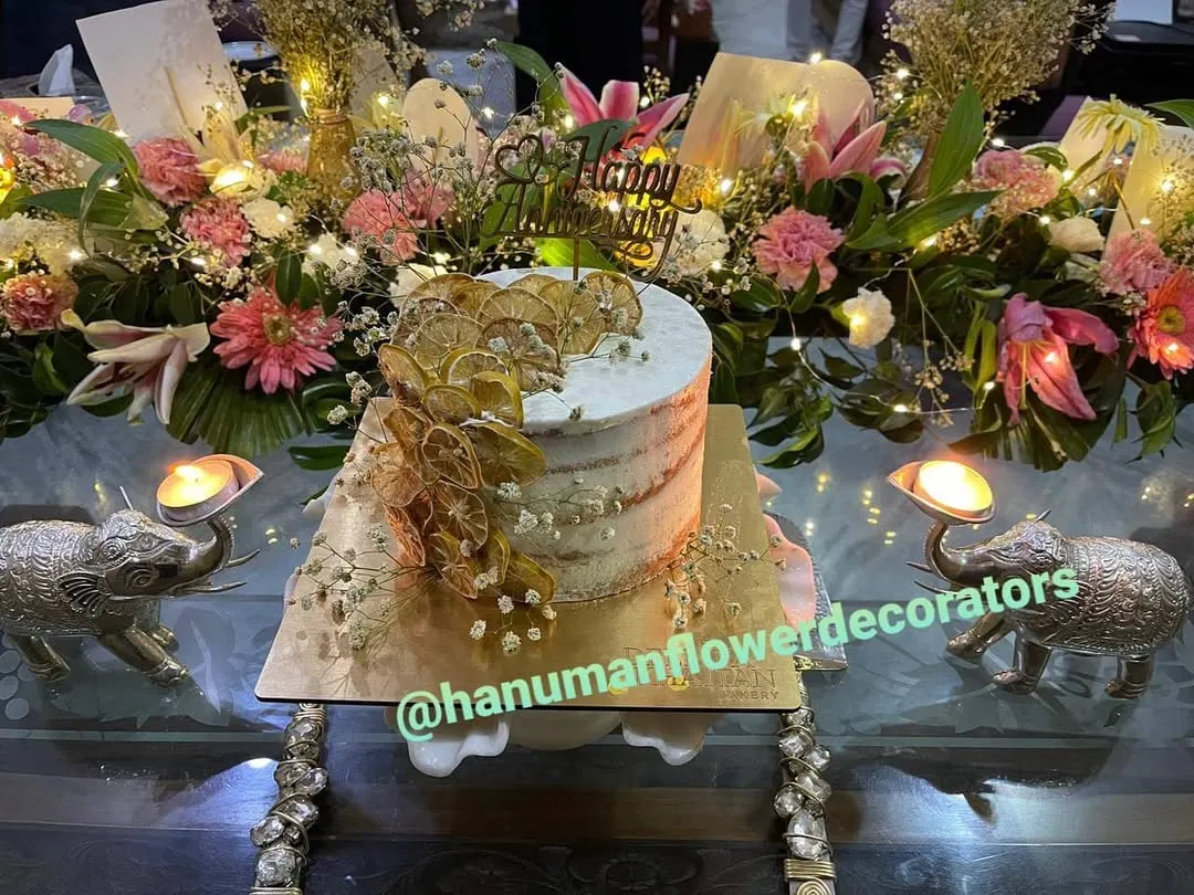 I can help you create a complete celebration centerpiece. This setup for a special birthday features a beautiful cake surrounded by a custom arrangement of fresh lilies, carnations, and baby's breath, accented with warm fairy lights.