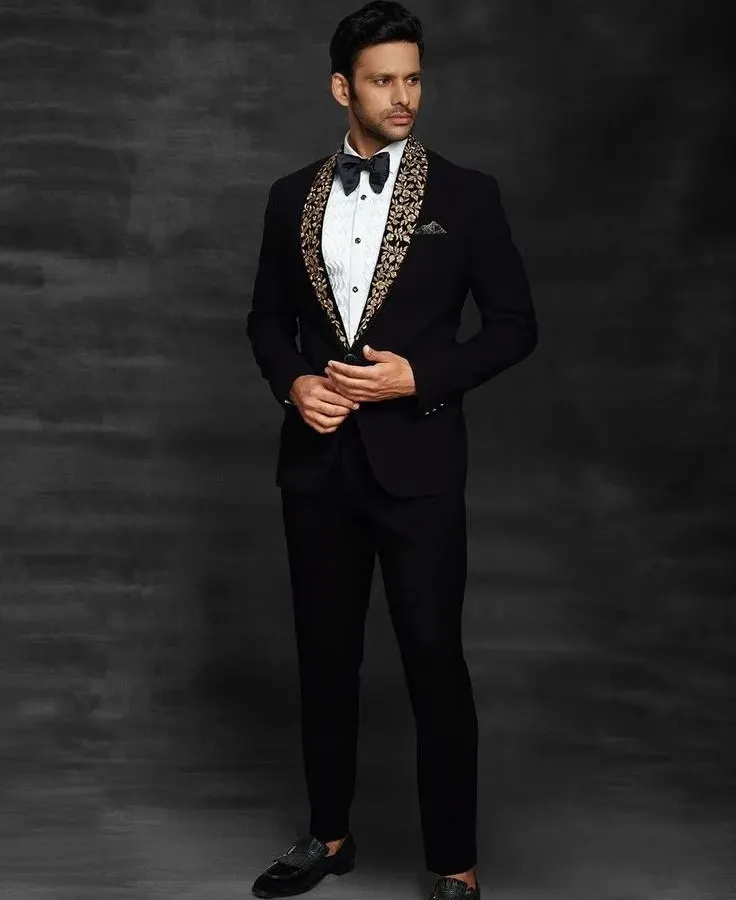 For a sharp reception or cocktail party look, nothing beats a custom-fit tuxedo. This black tuxedo features a unique embroidered shawl lapel, giving a modern twist to a classic style. It's all about looking sharp and sophisticated.