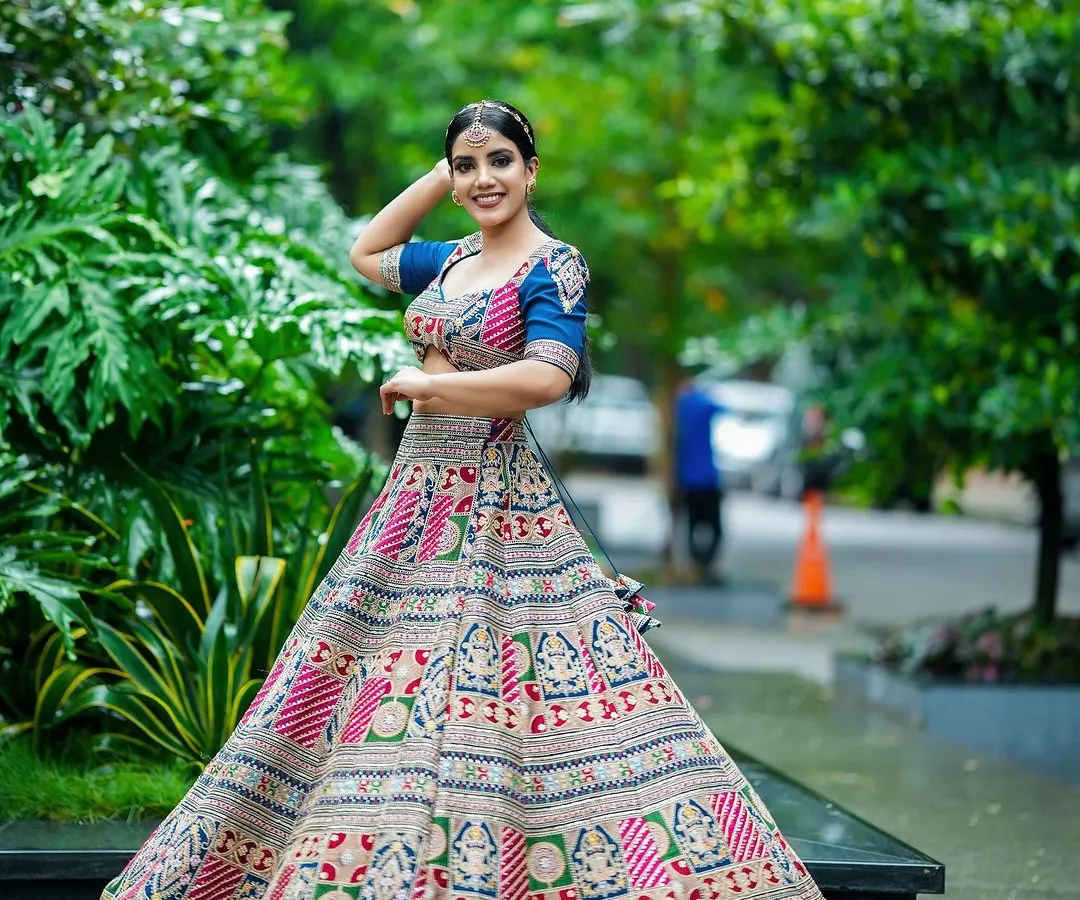We love capturing the life and movement of a garment. Here, a model twirls in a vibrant, multi-colored ethnic lehenga, showcasing the full skirt and intricate patterns against a lush garden backdrop. This is a key shot for any Indian wear catalogue.