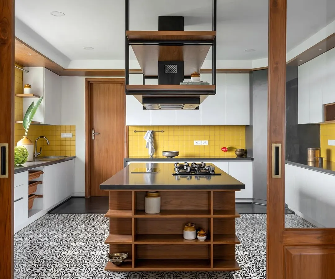 A kitchen should be full of life, and this island kitchen from 'Vasudhalayah' is just that. The bold yellow piccolo tile backsplash and Moroccan floor tiles create a vibrant energy, while the custom island with an integrated hob and overhead unit provides a highly functional culinary workspace.