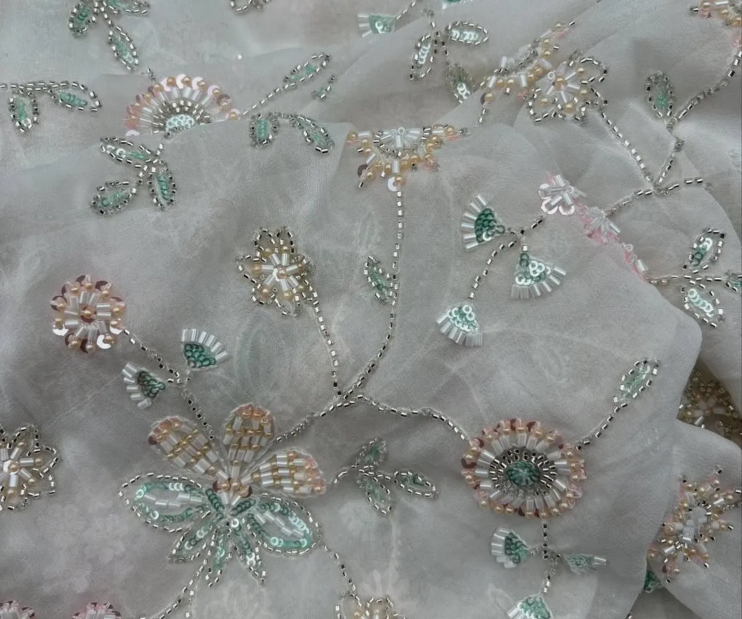 This is the kind of detail that makes an outfit unforgettable. The delicate, multi-tonal floral embroidery on this sheer georgette fabric creates a three dimensional effect, perfect for a custom wedding guest lehenga or a statement tunic.