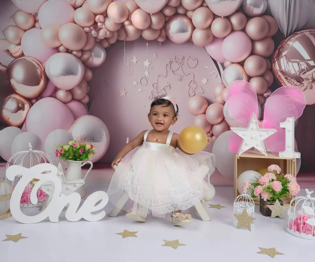 We captured the pure delight of this little one's first birthday. This milestone photoshoot features a custom-designed pink and silver balloon arch, creating a magical setting to celebrate such a special day.