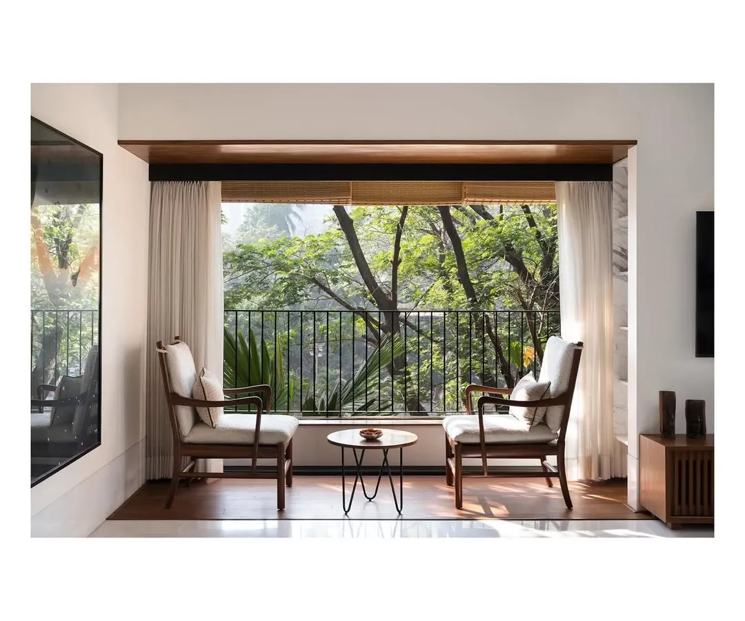 We create intimate moments within a home, like this quiet seating area for two. By perfectly framing the lush greenery outside, we turn a simple window into a private retreat, blending the interior with nature.