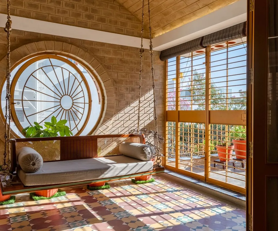 A quiet corner in the Audumbara house, where light, texture, and tradition meet. The vaulted brick ceiling, patterned cement tiles, and a large circular window create a serene, sunlit space that connects the indoors with the terrace garden.