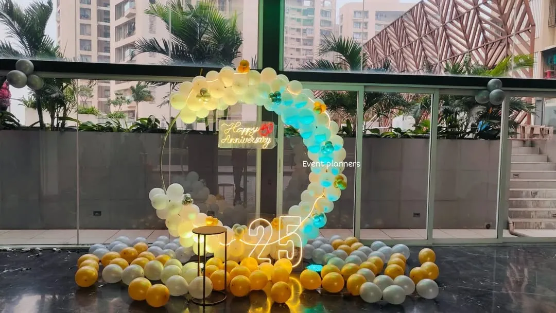 For a grand 25th anniversary celebration, I created this elegant circular balloon arch in a corporate lobby. The design combines white and gold balloons with dynamic lighting, a "Happy Anniversary" neon sign, and large marquee numbers to create a stunning photo opportunity.