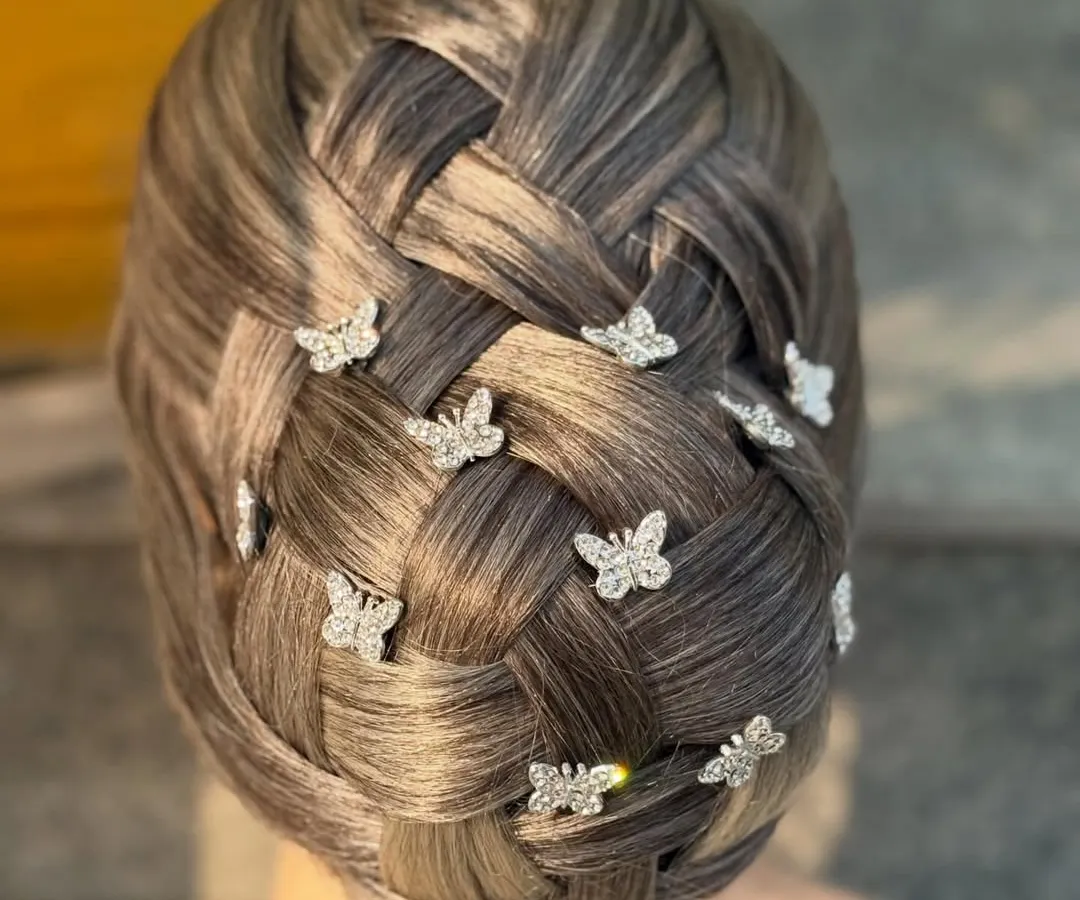 Mastering intricate techniques like this basket-weave updo is a core part of our advanced hairstyling course. We teach our students how to create clean, complex patterns and accessorize them with delicate details like these butterfly pins for a whimsical touch.
