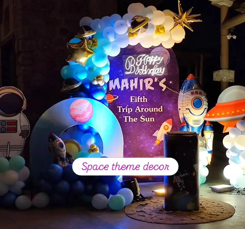 An out-of-this-world space-themed birthday party, complete with a galaxy backdrop, planet cutouts, rocket ship props, and a custom neon sign for the birthday boy.