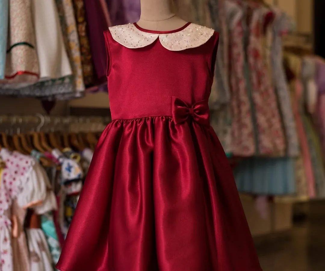 A timeless classic for any celebration, this A-line dress in rich red satin is simply elegant. The design features a sparkly white Peter Pan collar and a sweet bow at the waist, creating a polished and festive look for your little fashionista.
