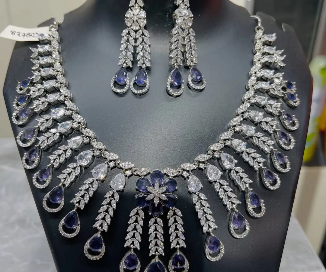 For a touch of classic elegance, this stunning necklace and earring set is a perfect choice. The intricate design combines brilliant clear crystals with deep sapphire-blue stones, making it an ideal rental for your reception or a formal evening party.