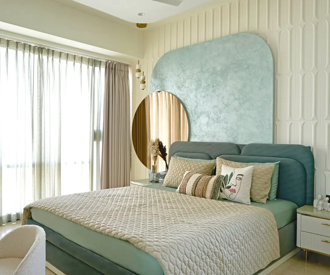 This serene master bedroom is a restful retreat anchored in a calming sage green palette. The design features a custom textured headboard and an MDF back wall, while a tinted mirror panel and fluted glass wardrobe add layers of understated luxury and functionality.