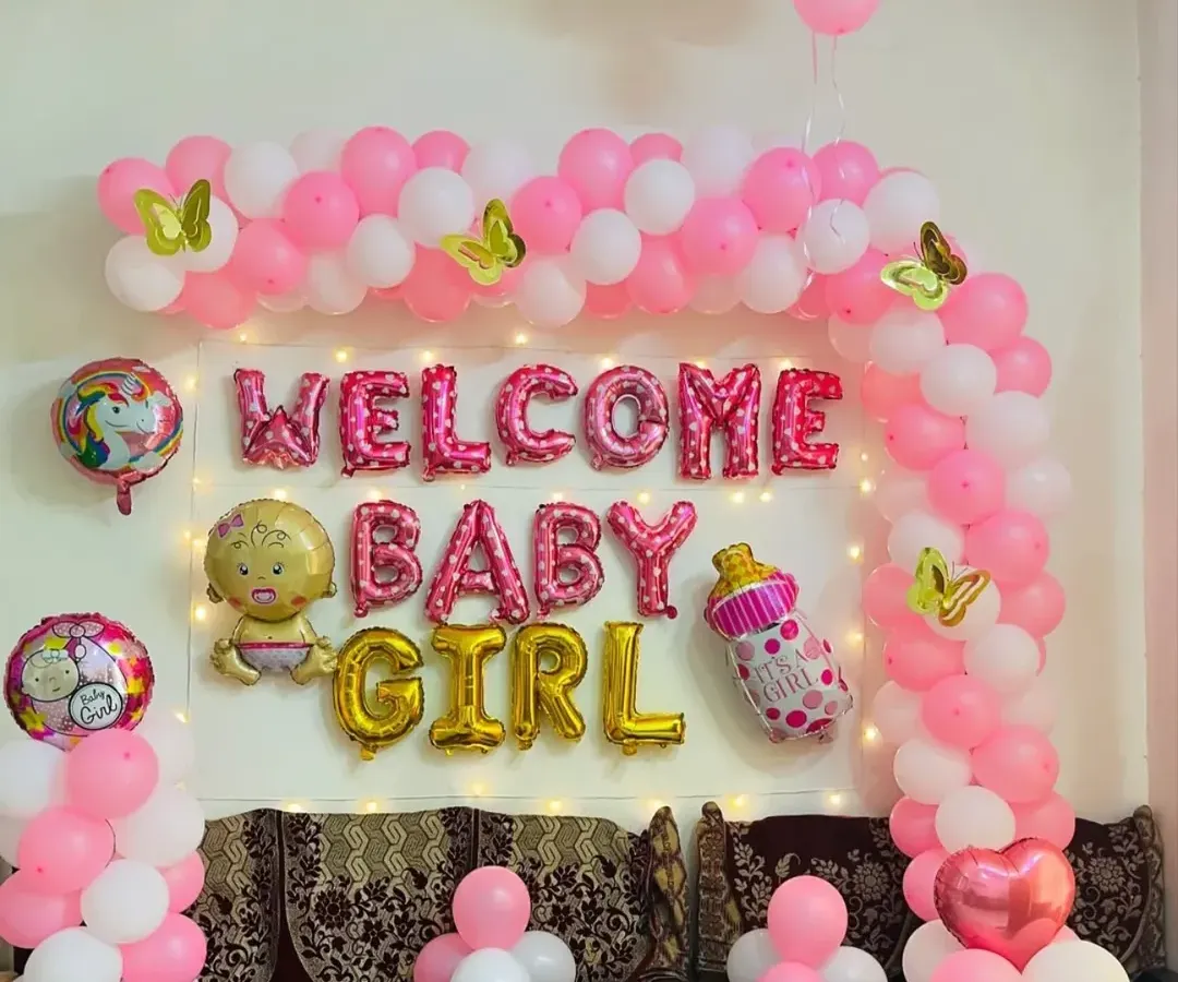 A classic and joyful "Welcome Baby Girl" decoration for a special homecoming. This arrangement includes a pink and white balloon arch, shimmering fairy lights, and charming foil balloons like a unicorn and a baby bottle to create a warm, celebratory atmosphere.