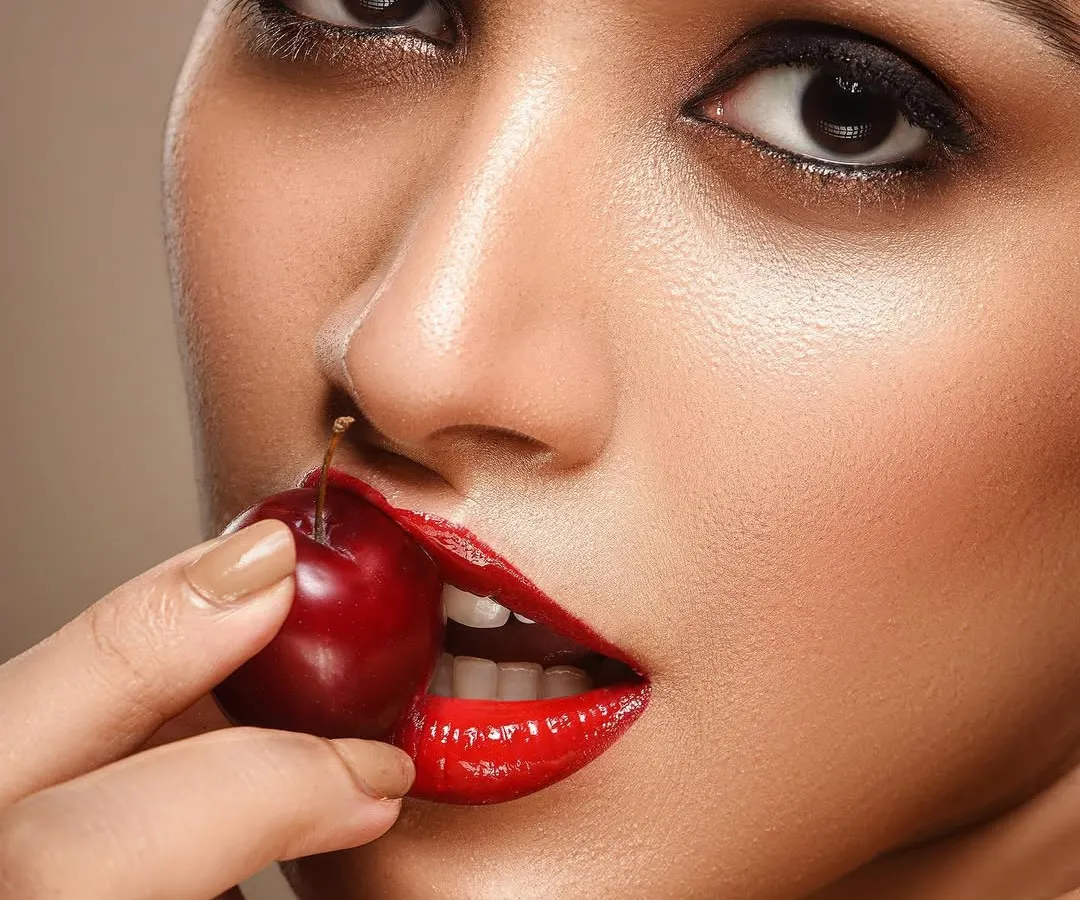 For beauty and cosmetic photography, the details are everything. This macro shot focuses on the flawless skin texture, the vibrant color of the lipstick, and the fresh look of the cherry, creating a bold and sensual image perfect for a skincare or makeup campaign.