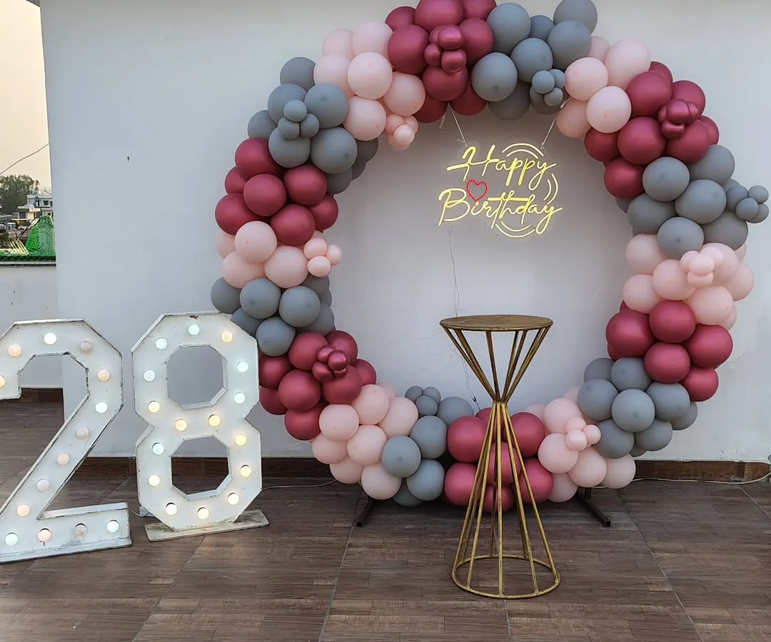 We do more than just bedrooms. This outdoor terrace setup for a 28th birthday features a custom balloon ring in a sophisticated maroon, pink, and grey palette, complete with a neon sign and large marquee lights. It’s perfect for making a big statement and creating an amazing photo corner.