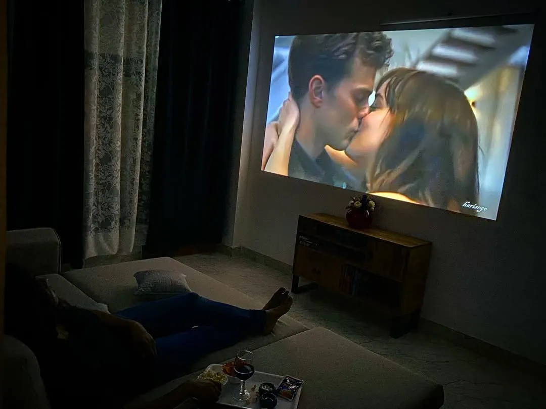Imagine this: just the two of you, relaxing on a comfy lounger with wine and popcorn, watching your favorite romantic movie on a giant screen. This is the private cinema experience I offer, right in your room.