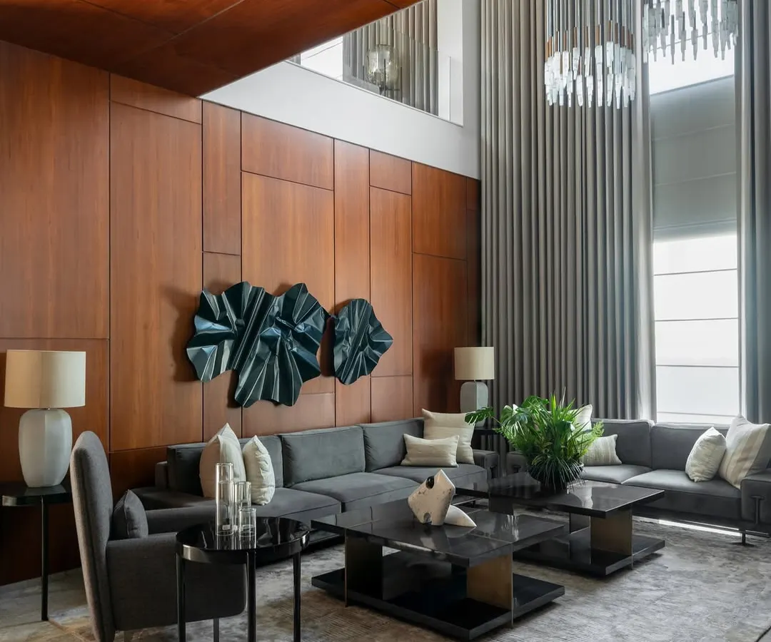 The double-height living room in this contemporary home uses expansive glass and soaring curtains to create a sense of grandeur. I balanced the scale with warm wood paneling and a monochromatic palette to keep the space inviting and elegant.