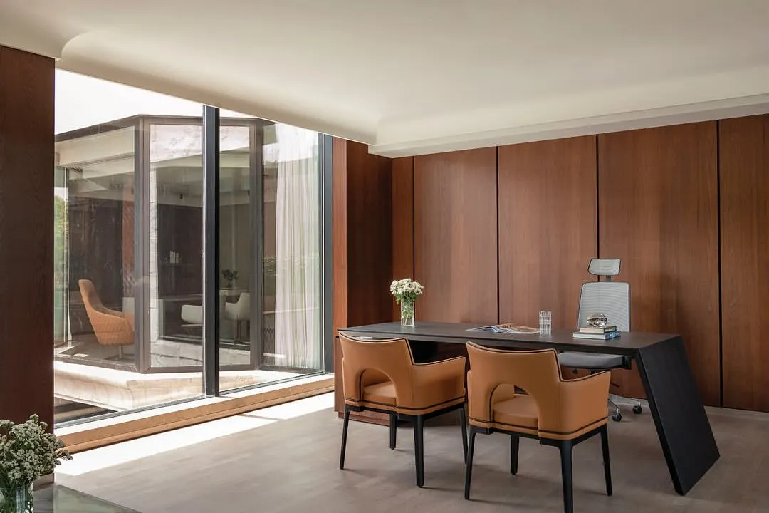 A director's cabin from our 'Layered Office' project, tailored to the user's taste. The design features rich wood paneling and a seamless connection to an outdoor courtyard, creating a spacious and personalized executive workspace that balances authority with comfort.