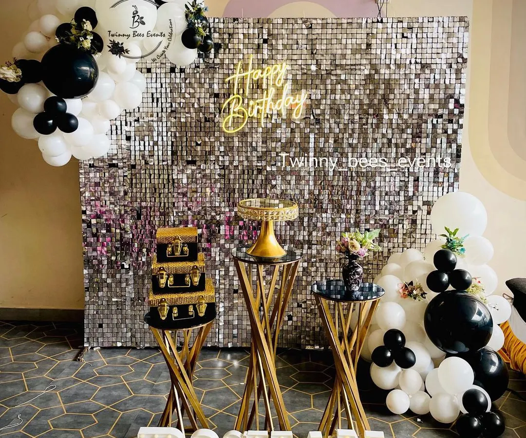 For a chic and modern milestone birthday, we designed this stunning silver sequin shimmer wall. The black and white balloon garland, custom marquee letters, and elegant dessert stands create a glamorous photo-op for any adult celebration.