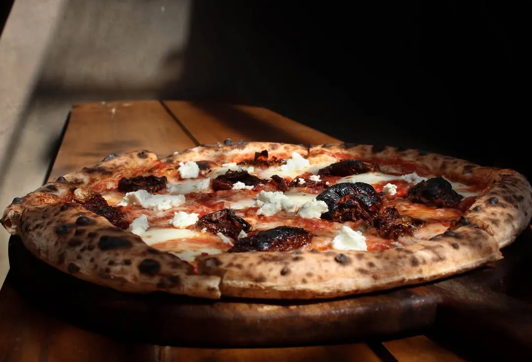 Our Smokey Marzano pizza soaking up the sun. It features a classic combination of sundried tomatoes, garlic, feta, and our hand-stretched mozzarella on a sourdough base.
