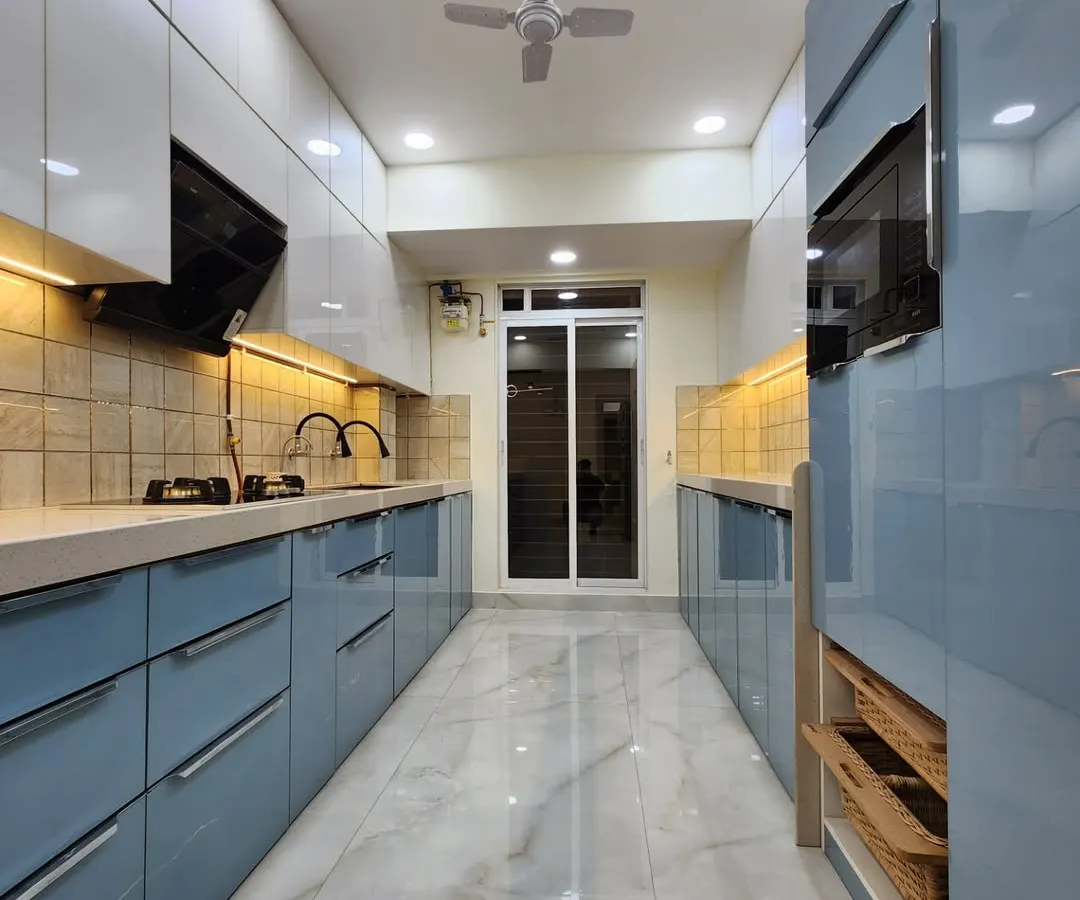 This is a parallel modular kitchen we designed for maximum efficiency and style. It features high-gloss acrylic finish cabinets in a calming powder blue and white, handleless drawers for a clean look, and integrated space for appliances, showcasing our ability to create functional yet beautiful kitchen layouts.